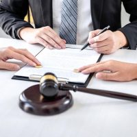 Divorce lawyer in Dubai signing separation papers with wedding rings and a gavel on the desk