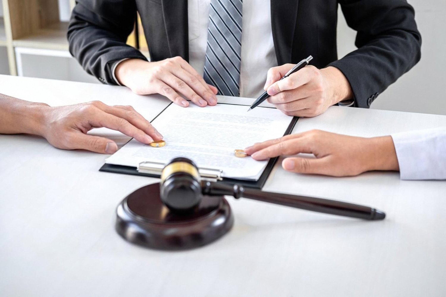 Divorce lawyer in Dubai signing separation papers with wedding rings and a gavel on the desk